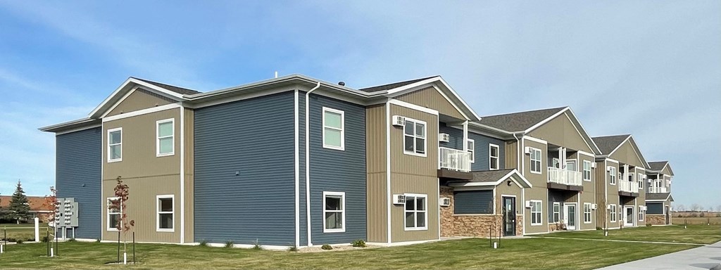 an apartment building with blue siding and a sidewalk