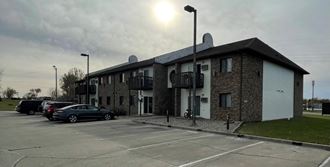 an apartment building with cars parked in a parking lot