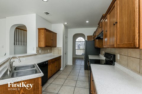 a kitchen with white counter tops and wooden cabinets and a sink