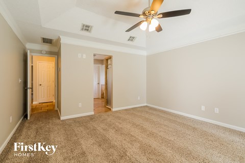 a spacious living room with carpet and a ceiling fan