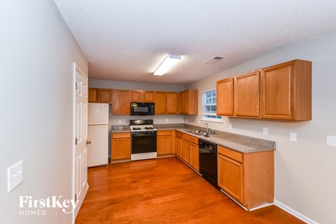 a kitchen with wooden cabinets and white appliances and a wood floor