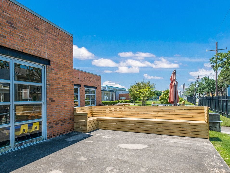 the patio of a building with a large wooden bench