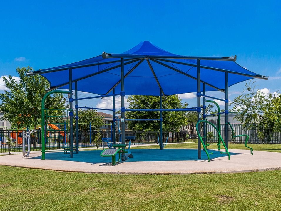 a playground with a blue pavilion with a swing set