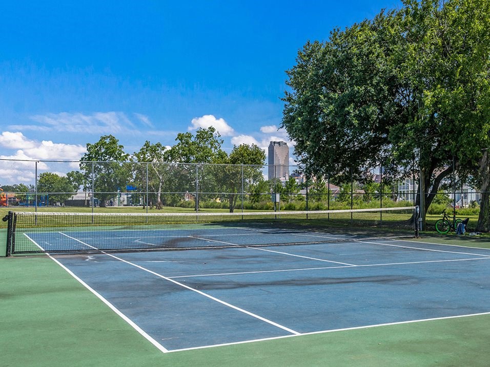 a tennis court with trees and a fence