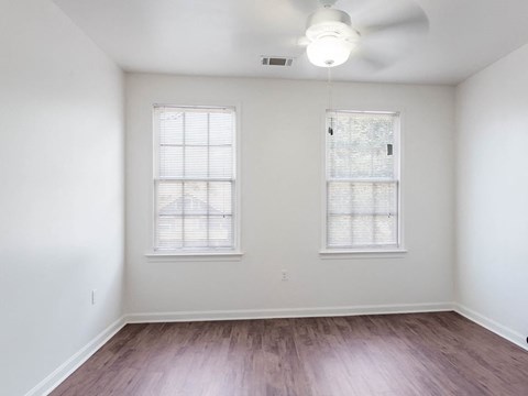an empty living room with wood floors and two windows