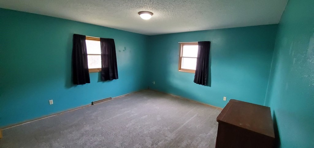 a room with blue walls and two windows with black curtains