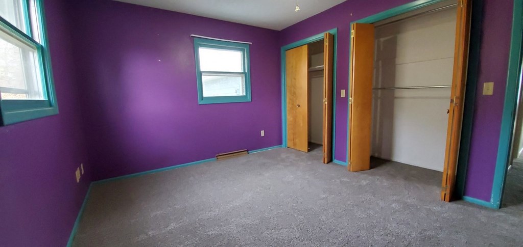 a room with purple walls and two doors and a window