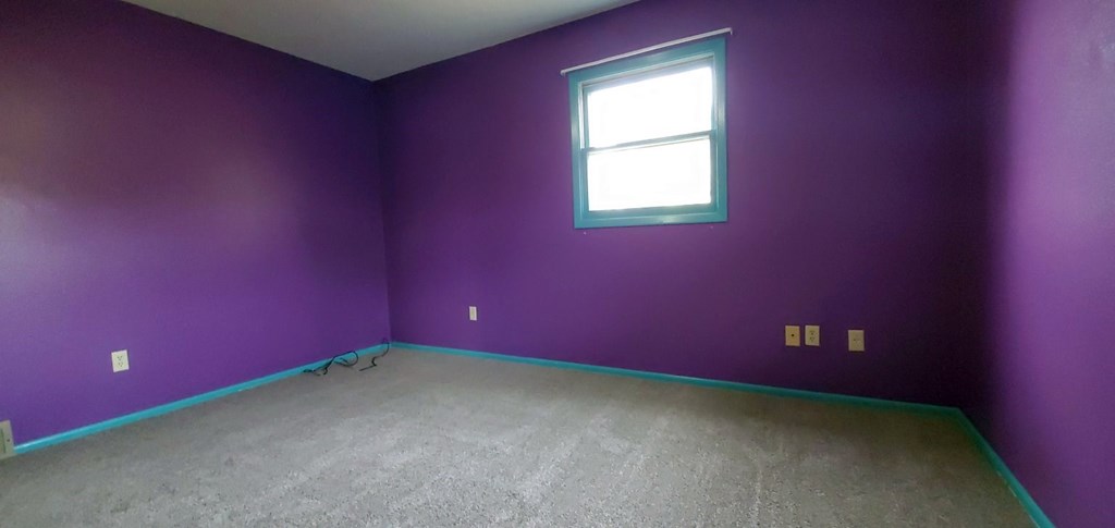 a room with purple walls and a window and a carpet