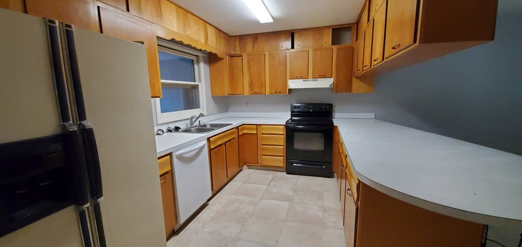 an empty kitchen with wooden cabinets and a white counter top