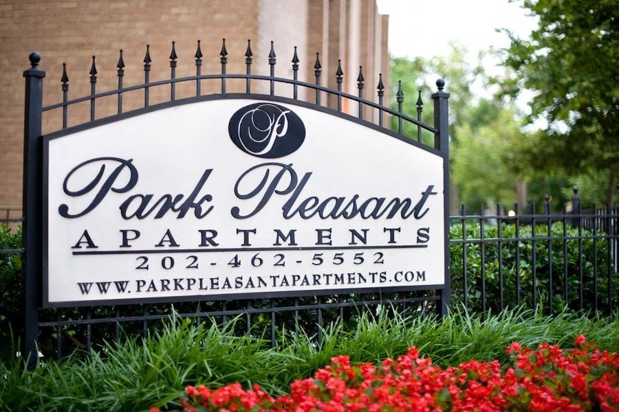 a sign for park pleasant apartments in front of a fence
