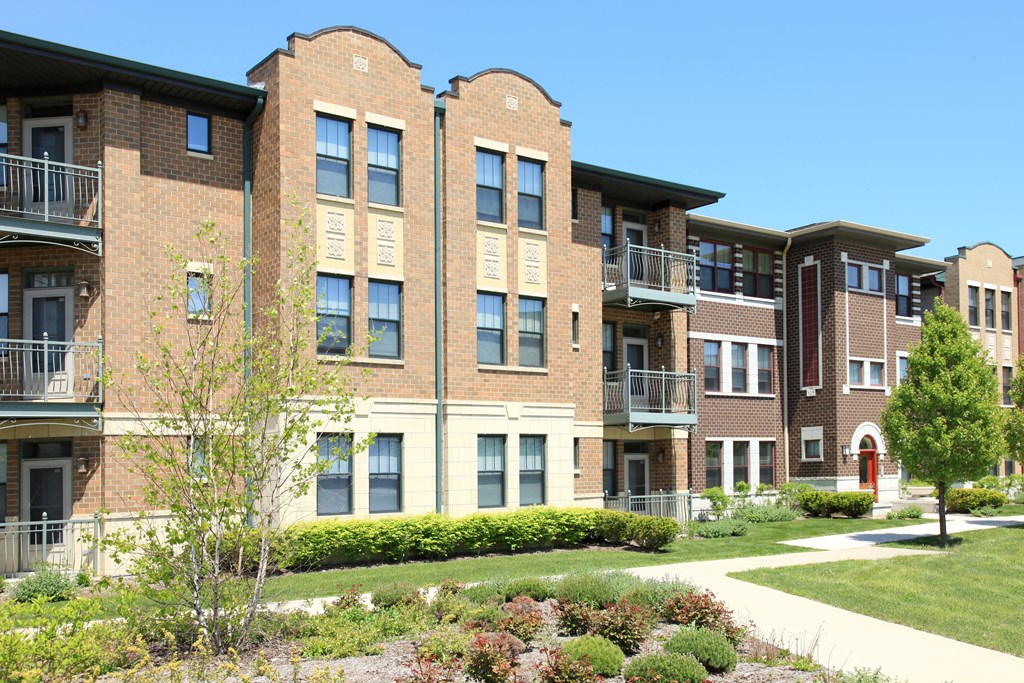 a brick apartment building with a sidewalk in front of it