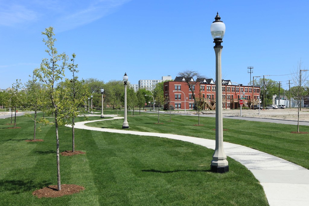 a park with trees and lamp posts and a sidewalk