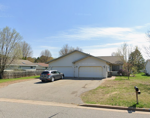 A car is parked in a driveway in front of a house.