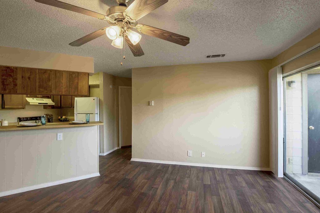 an empty living room and kitchen with a ceiling fan