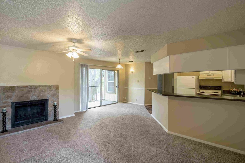 an empty living room with a fireplace and a kitchen
