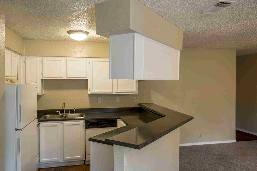 an empty kitchen with white cabinets and a counter top