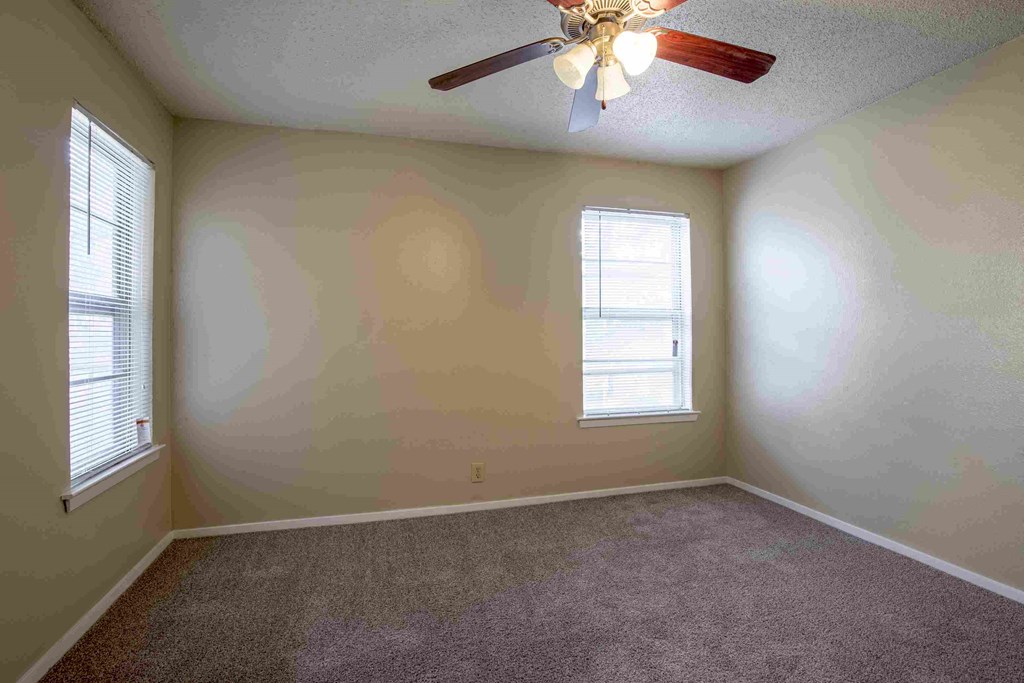 an empty living room with a ceiling fan