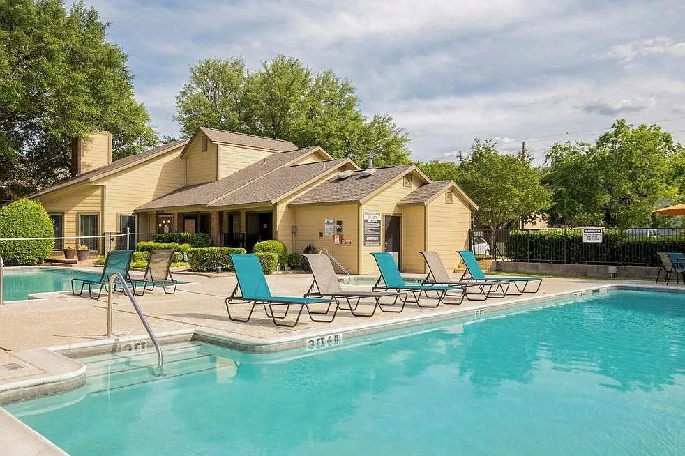 a swimming pool with blue chairs next to a house