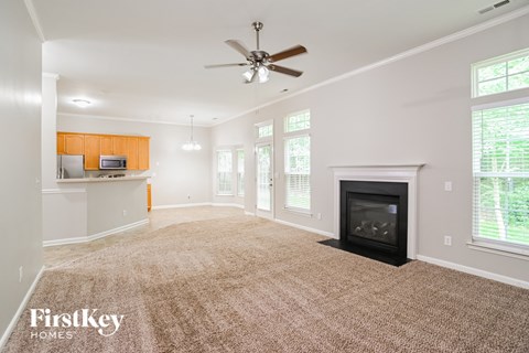 A spacious living room with a fireplace and a ceiling fan.