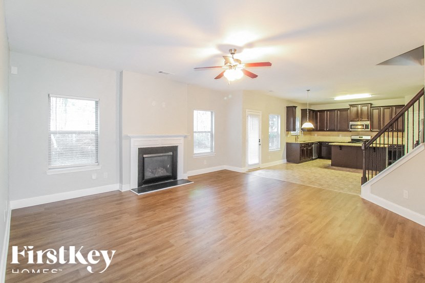 an empty living room with a fireplace and a ceiling fan