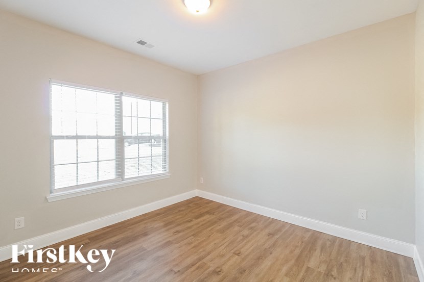 the spacious living room with hardwood flooring and two windows