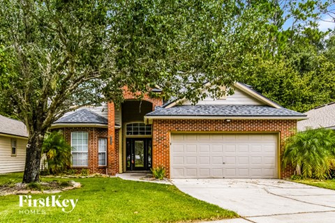 a brick house with a white garage door and a tree