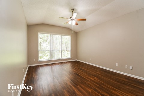the spacious living room with hardwood flooring and a large window