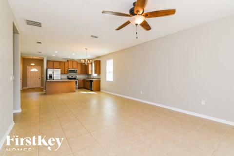 A spacious living room with a ceiling fan and tiled flooring.