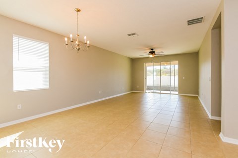 A spacious room with a chandelier, ceiling fan, and sliding glass doors.
