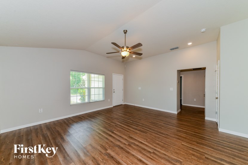 A spacious room with wooden floors and a ceiling fan.