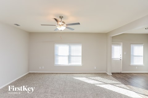 a living room with a ceiling fan and a carpet