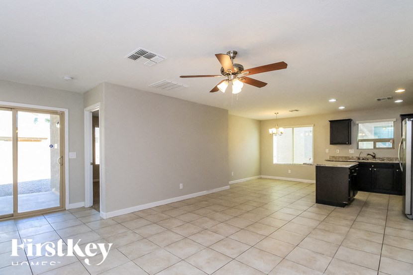 A spacious room with a ceiling fan and a kitchenette.