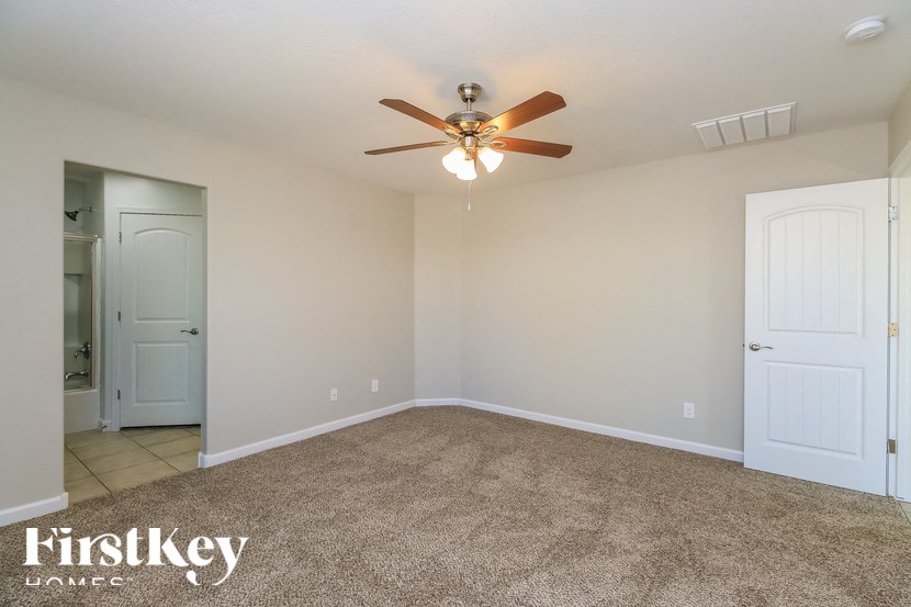 A room with a ceiling fan and carpeted floor.