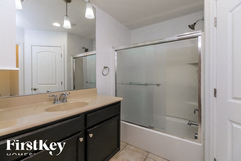 A bathroom with a sink, mirror, and shower.