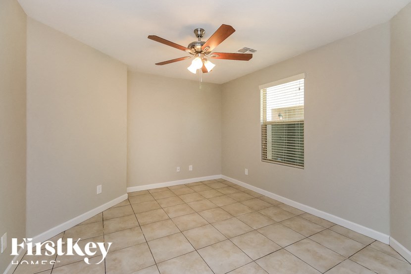 A room with a ceiling fan and a window with blinds.