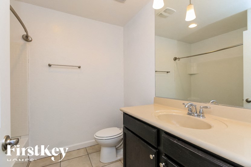 A bathroom with a toilet, sink, and mirror.