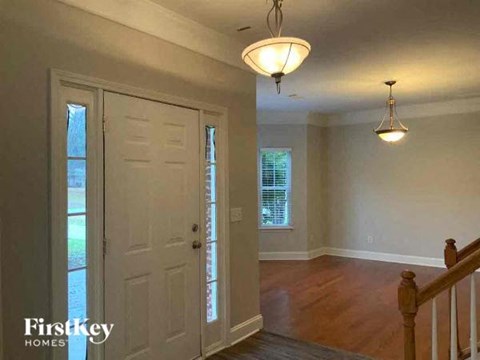 an empty living room with a staircase and a white door