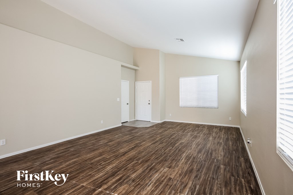 the living room of an apartment with wood flooring and white walls