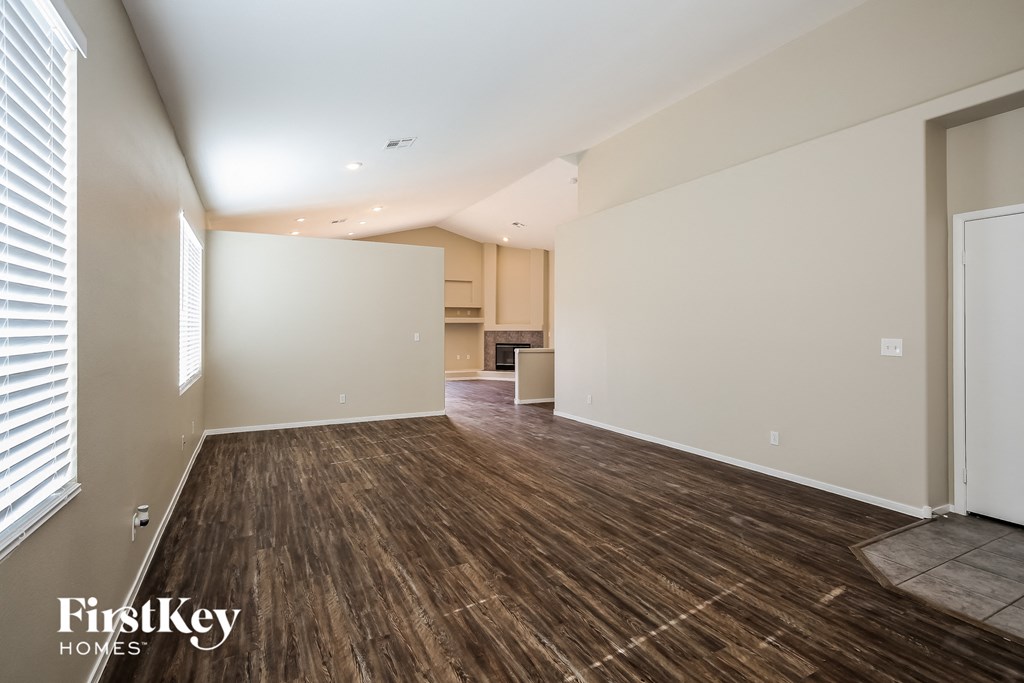 the living room and kitchen of an empty house with wood flooring
