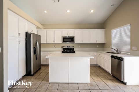 a large kitchen with white cabinets and stainless steel appliances