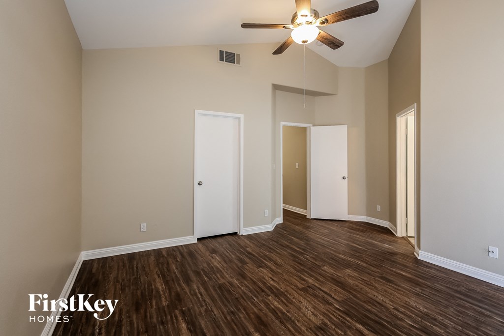 an empty living room with wood flooring and a ceiling fan