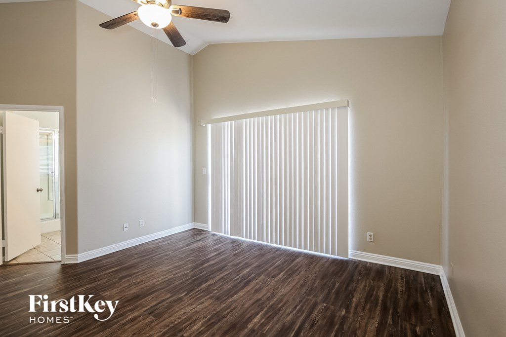 a living room with wood flooring and a large window with white blinds