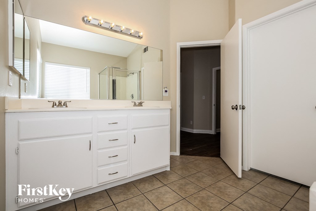 a bathroom with white cabinets and a large mirror