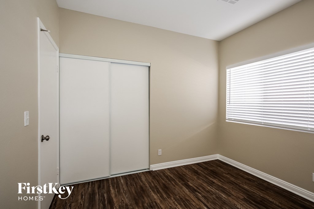 a bedroom with a closet and a window and wooden floors