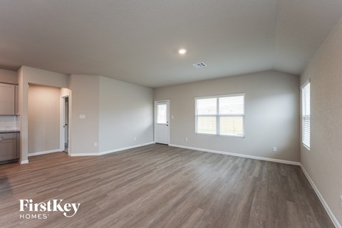 A spacious room with wooden flooring and a window with blinds.