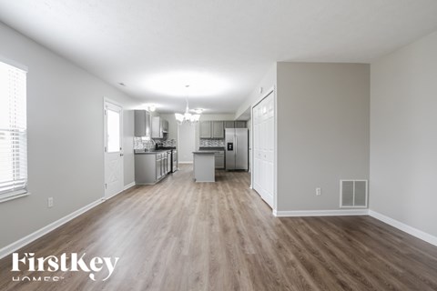 A spacious kitchen with wooden floors and white walls.