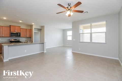 A spacious living room with a kitchen area in the background.
