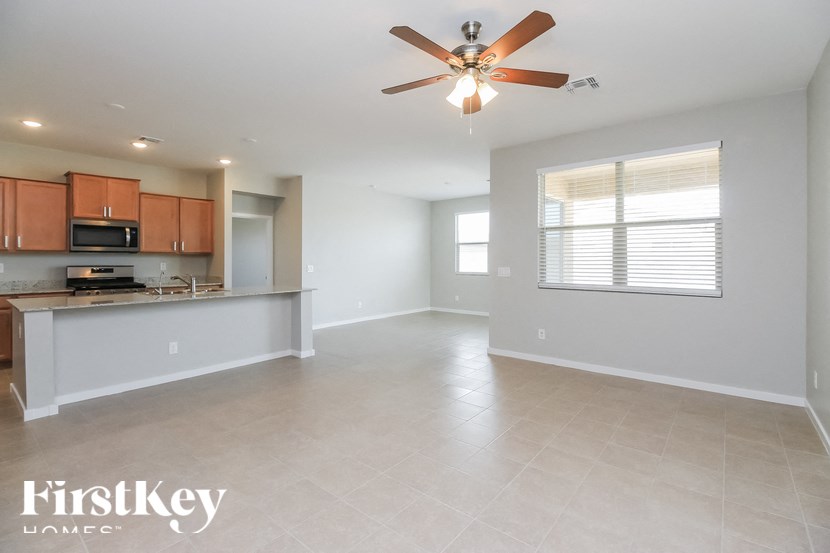 A spacious living room with a kitchen area in the background.