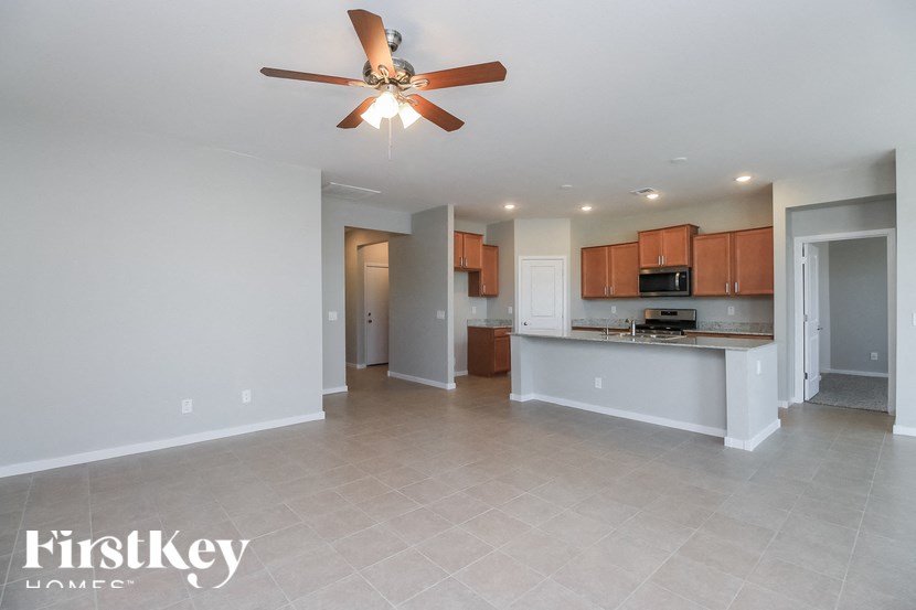 A spacious room with a ceiling fan and a kitchen area in the background.