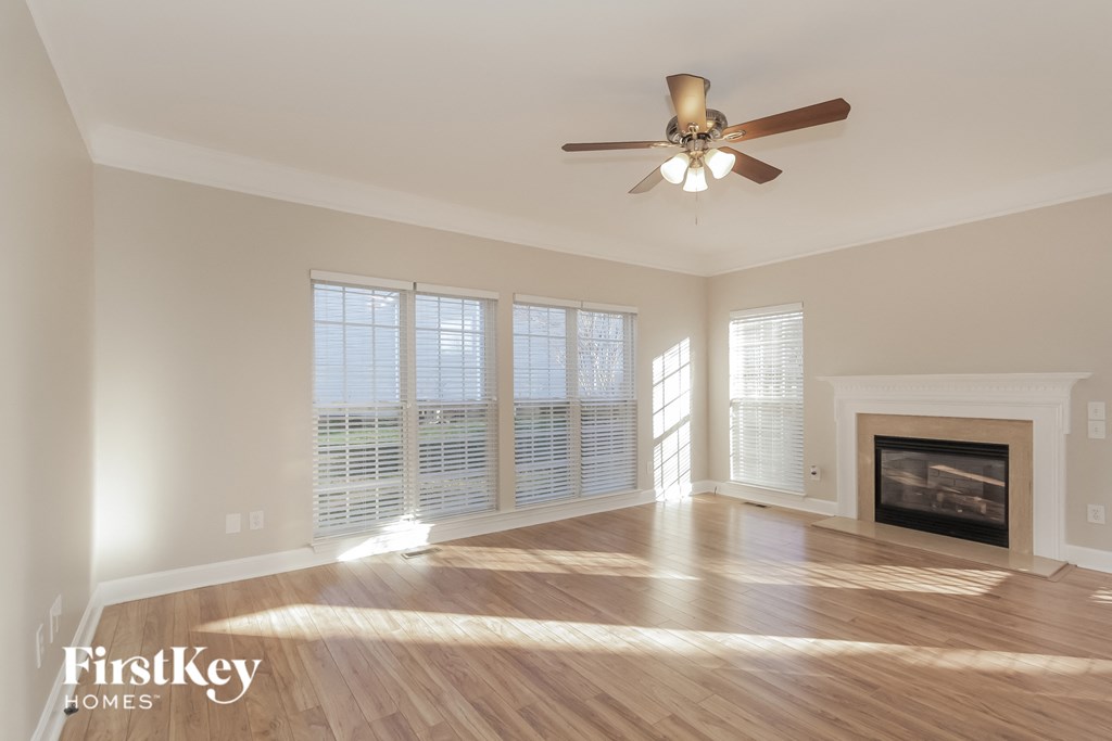 an empty living room with a ceiling fan and a fireplace